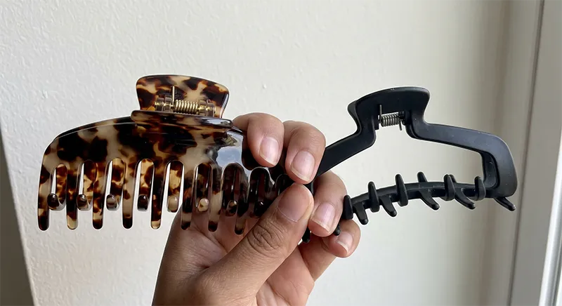 Close-up comparison of cellulose acetate jaw clip and standard ABS plastic jaw clip showing surface finish and hinge construction differences