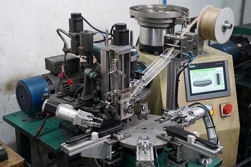 Hair brush bristle setting process on a factory production workstation with tools and components visible