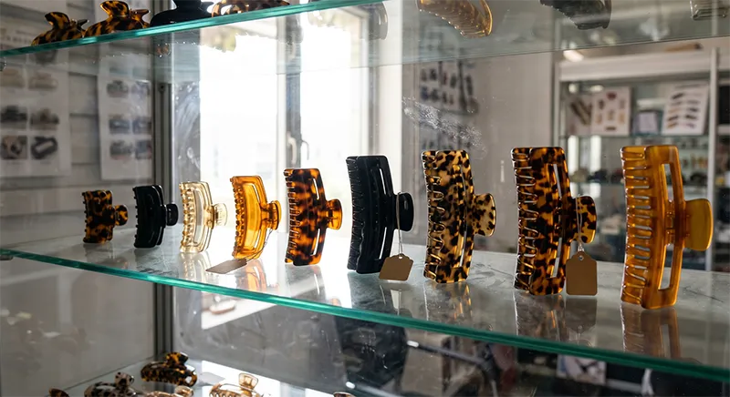 Acetate jaw clips in multiple sizes displayed on a factory showroom shelf for thick hair product line review