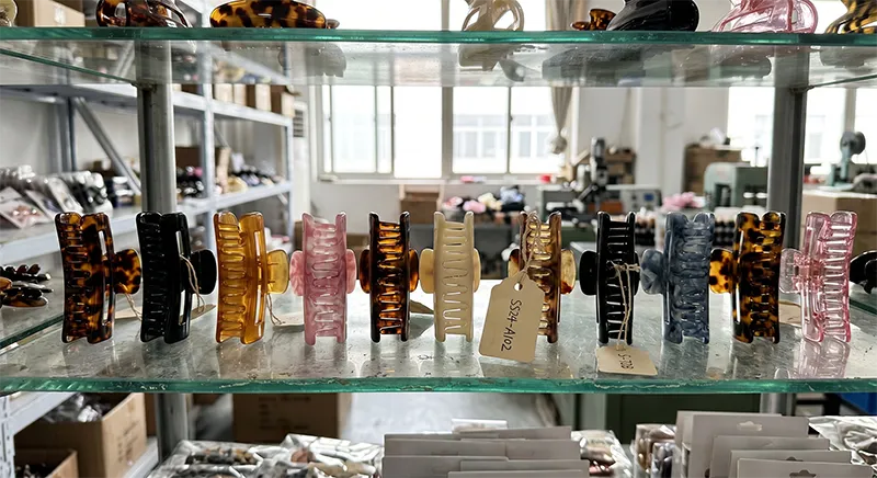 Acetate claw clip samples in various colours and sizes displayed on a manufacturer showroom shelf for private label buyer review