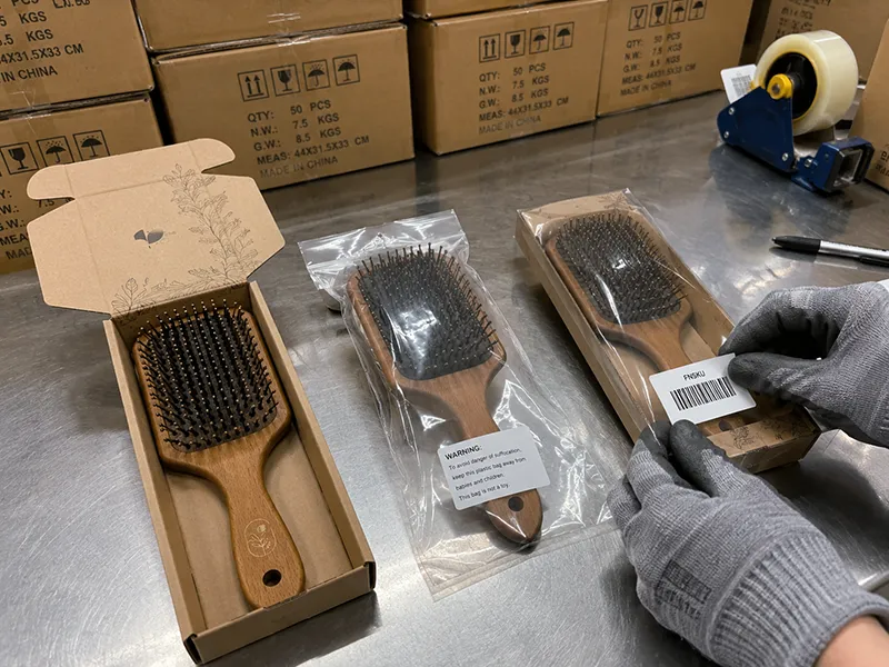 Custom paddle brushes in branded retail packaging ready for Amazon FBA shipment with FNSKU labels and carton preparation visible