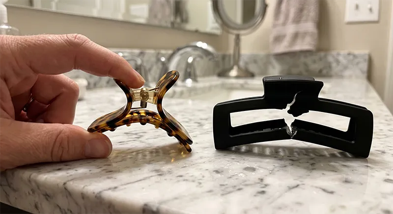 Side by side demonstration of an acetate clip flexing under pressure versus an ABS plastic clip with a visible crack at the hinge point