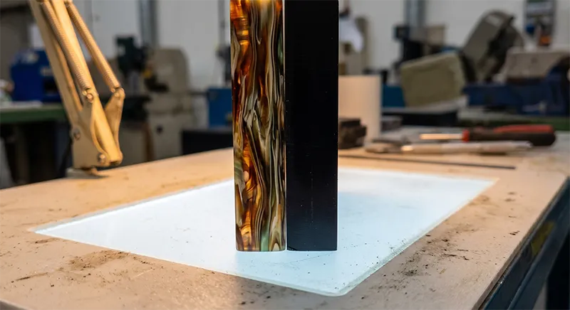 Close-up cross-section comparison of cellulose acetate sheet showing layered colour depth versus ABS plastic showing uniform solid colour