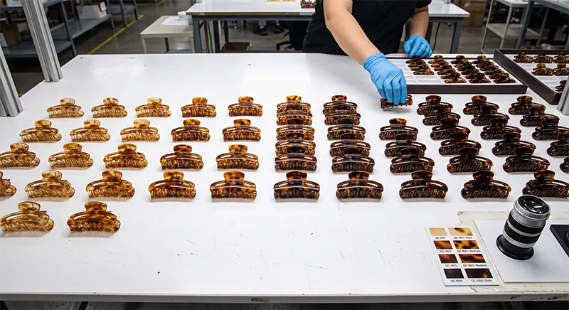 Rows of finished acetate claw clips sorted by colour on a factory quality inspection table ready for final checking and packing