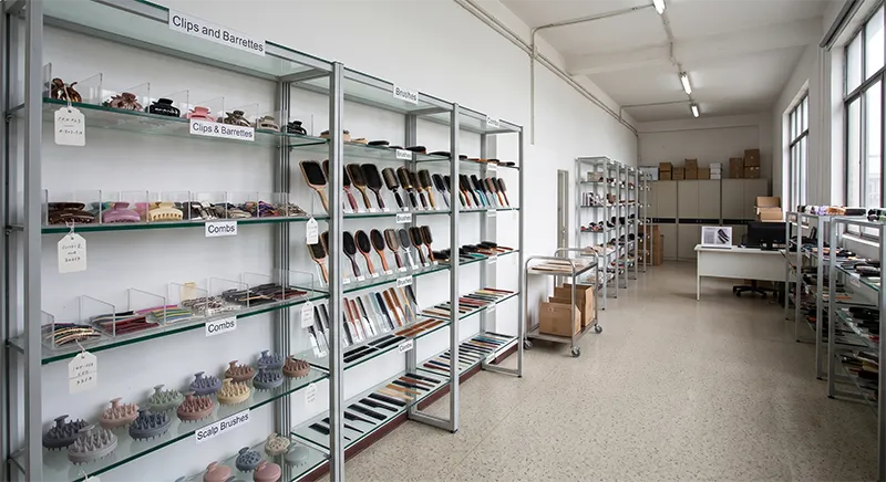 Hair accessories factory showroom in China displaying hair clips, brushes, combs, and scalp brushes across glass shelves for buyer evaluation
