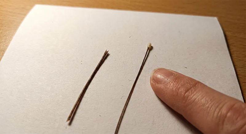 Two hair strands side by side showing the difference between breakage with no root bulb and natural shedding with a white root bulb visible