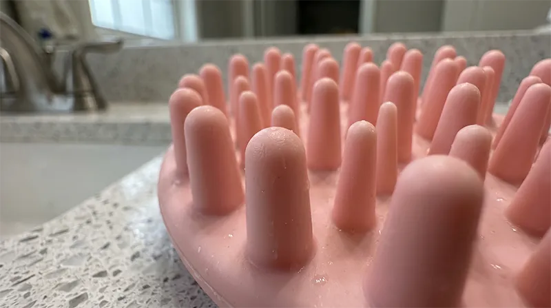 Close-up of a silicone scalp massage brush showing the soft flexible bristle tips designed for gentle scalp stimulation without scratching