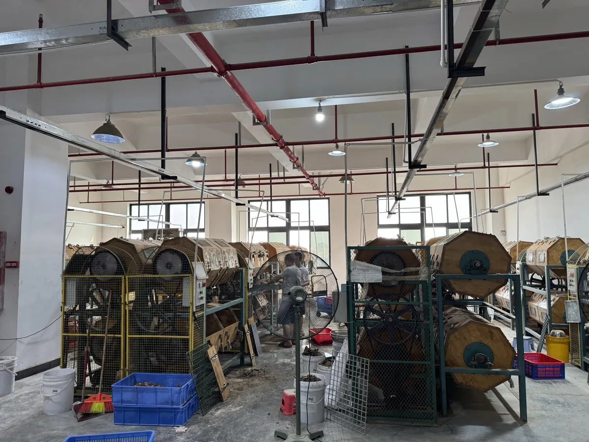 Row of wooden tumbling barrels used to polish acetate hair clip parts